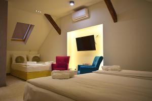 萨拉热窝Deluxe Nortel Hotel的一间设有两张床和两把椅子的房间以及一台电视