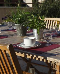 卡尔卡松阿多尼斯卡尔卡松公寓式酒店的木桌,上面有盘子和玻璃杯,上面有植物