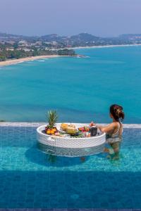 苏梅岛Villa Anushka - Modern luxury villa with picture-perfect sea views的水中的女人,在游泳池里带桌子