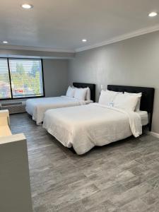 安纳海姆Capri Suites Anaheim的两张位于酒店客房的床,配有两张sidx sidx单人床