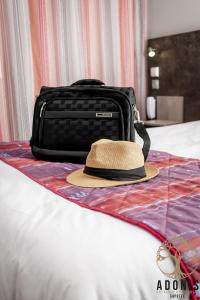 加普Adonis Gapotel的手提箱旁边的床上的帽子