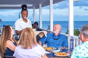 伯利兹城Harbour View Boutique Hotel & Yoga Retreat的一群坐在桌子旁吃食物的人