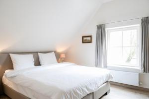 奥斯特坎普Loweide Lodges & Holiday Homes near Bruges的白色的卧室设有一张大床和一个窗户