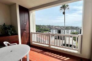 乌旺戈海滩Seaview Beachfront Holiday Apartment - 164 Laguna La Crete的阳台配有白色桌子和棕榈树。