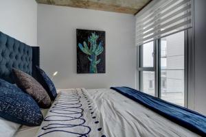 魁北克市Les Immeubles Charlevoix - 760-505的一间卧室配有一张带蓝色枕头的床和一扇窗户。