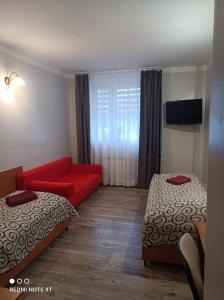 奥斯特罗维茨Willa-Restauracja Victoria的酒店客房带两张床和一张红色沙发