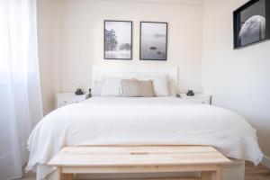 维戈SAMIL PLAYA SUR的白色卧室配有白色的床和墙上的三张照片