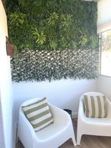 维戈SAMIL PLAYA SUR的一间设有绿色墙壁、白色沙发和椅子的客房