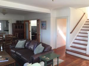 太平洋丛林3118 Yellow House Main home的客厅设有棕色皮革沙发和楼梯。