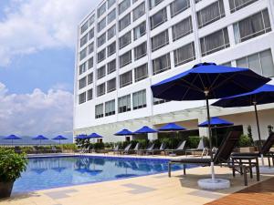太平太平诺富特酒店的酒店设有带蓝伞和椅子的游泳池