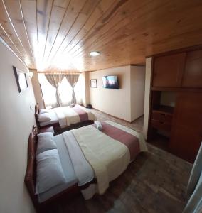 帕斯托Hotel Buenaventura的一间带两张床的卧室,位于一个拥有木制天花板的房间