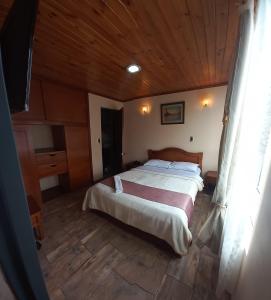 帕斯托Hotel Buenaventura的一间卧室设有一张床和木制天花板