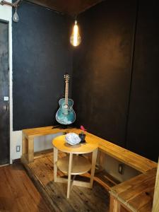 大阪Backstage Party Hostel & Bar的墙上有吉他桌,凳子桌子