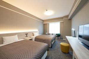 仓敷The OneFive Garden Kurashiki的酒店客房设有两张床和一台平面电视。
