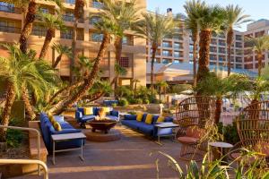 印第安维尔斯Renaissance Esmeralda Resort & Spa, Indian Wells的一个带蓝色沙发和棕榈树的度假庭院