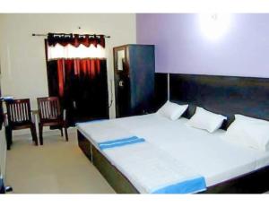 阿姆利则Hotel Kailash, Amritsar的一间卧室配有一张大床和两把椅子
