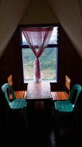 巴纳韦Batad Hillside Inn and Restaurant的窗户间里的一张桌子和两把椅子