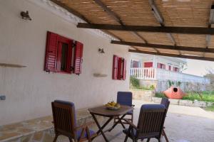 Makris GialosYasemia Wood & Stone Villa的一个带桌椅和红色百叶窗的庭院