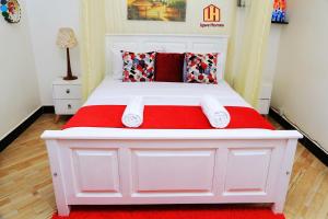坎帕拉Igwe Homes - Kisaasi的一张白色的床,上面有红色的毯子和枕头