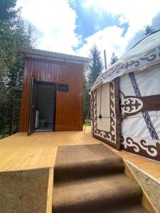 DzhetyoguzYurty Mc yurt的一座大型建筑,在木甲板上铺着地毯