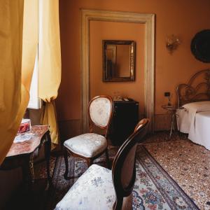 摩德纳萨洛托阿尔阿提酒店的一间设有两把椅子、一张床和镜子的房间