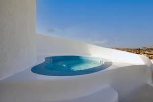 Éxo GoniáAecon Suites的白色建筑中的一个小蓝色浴缸