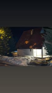 新帕扎尔Vikendica Golija的白色的房子,有棕色的屋顶和一棵树
