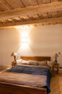 西克斯特Gîte ferme en permaculture avec ses animaux的一间带一张大床的卧室,位于一个拥有木制天花板的房间
