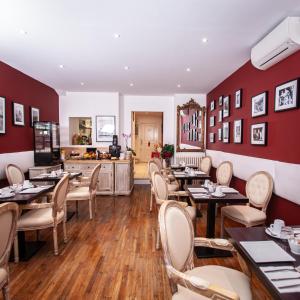 波尔多波尔多中心丘吉尔酒店的餐厅设有木桌和椅子,拥有红色的墙壁