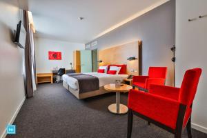 列日酷洛内列日酒店的酒店客房,配有床铺和红色椅子