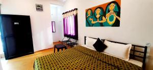 萨瓦伊马多普尔Ranthambhore Tiger Valley的卧室配有一张床,墙上挂有绘画作品