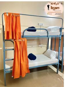 马迪凯里iKyam (The Backpackers Hostel/Homestay)的配有橙色窗帘的客房内的两张双层床