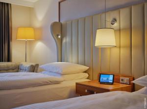 波恩Dorint Hotel Bonn的酒店客房设有两张床和一张桌子上的笔记本电脑