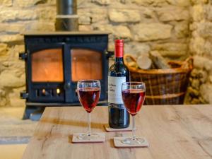 北伍顿Mulberry Cottage的木桌旁放着两杯红葡萄酒