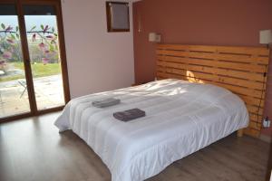 MeyriéMaison 3 chambres, 3 SdB, terrasse, piscine, spa的卧室配有白色的床和木制床头板