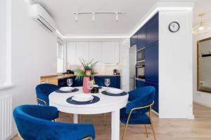 克拉科夫Fredry 6 Apartment Premium Łagiewniki by Renters Prestige的厨房配有白色的桌子和蓝色的椅子