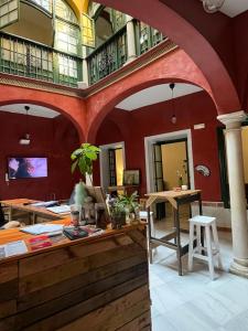 塞维利亚San Isidoro Hostel Sevilla的大房间设有红色的墙壁和桌椅