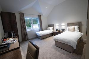 LaxeyShore Hotel Laxey的一间卧室设有两张床、一台电视和一扇窗户。