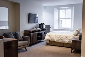 LaxeyShore Hotel Laxey的一间卧室配有一张床、一台电视和一把椅子