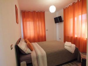 Căpăţîneni-Ungurenilivada-cu-meri的一间卧室配有带橙色窗帘的床和电视。