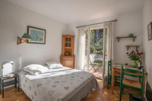 圣保罗-德旺斯Le Mas des Gardettes的一间卧室配有一张床、一张桌子和一个窗户。