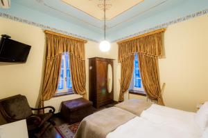 波尔塔里亚阿肯提克纳欧米迪酒店的一间卧室配有一张床和一把椅子,还有两个窗户