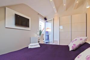 斯普利特劳拉力士套房酒店的一间卧室配有一张紫色床,墙上配有电视