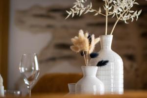 昂热Love Room Bohème Les Petits Plaisirs的两只带羽毛的白色花瓶,放在桌子上,放上玻璃