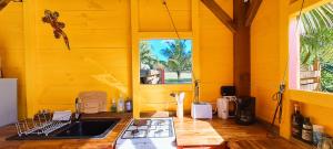 圣安尼Yuka Lodge - Bungalow privé avec jardin en pleine nature的黄色的厨房,配有水槽和窗户