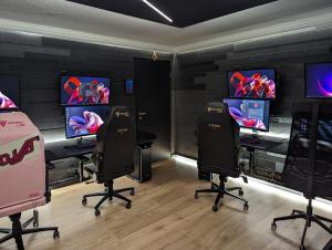 凯夫拉维克Smart Luxury - Gaming Arena, Gym, Sauna and Jacuzzi的配有四把椅子和游戏机的电子游戏室