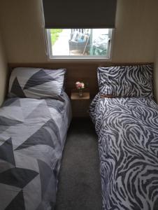 康威A22 is a 3 bedroom caravan on Whitehouse Leisure Park in Towyn near Abergele with decking and close to sandy beach的小型客房 - 带2张床和窗户