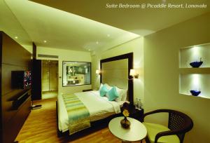 罗纳瓦拉Meritas Picaddle Resort Lonavala的酒店客房,配有一张床、一张桌子和椅子