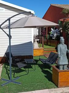 弗雷瑞斯Mobile home Zen Siblu Fréjus的院子里的一把遮阳伞和椅子以及雕像
