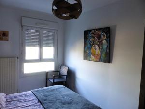 马孔Appartement cosy 4 personnes的卧室配有一张床,墙上挂有绘画作品